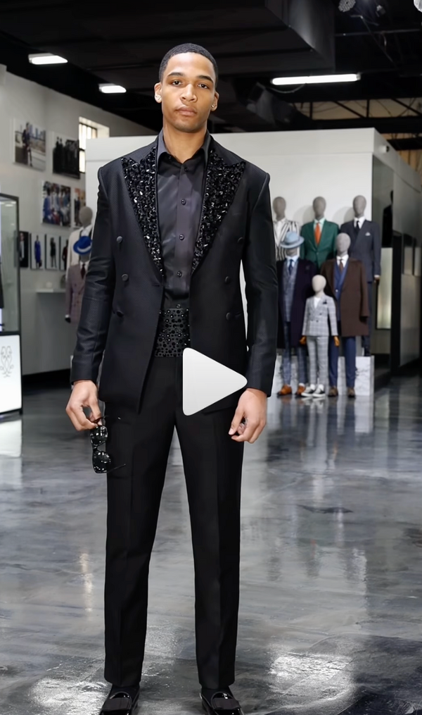 Man in decorative black suit standing in a modern showroom setting