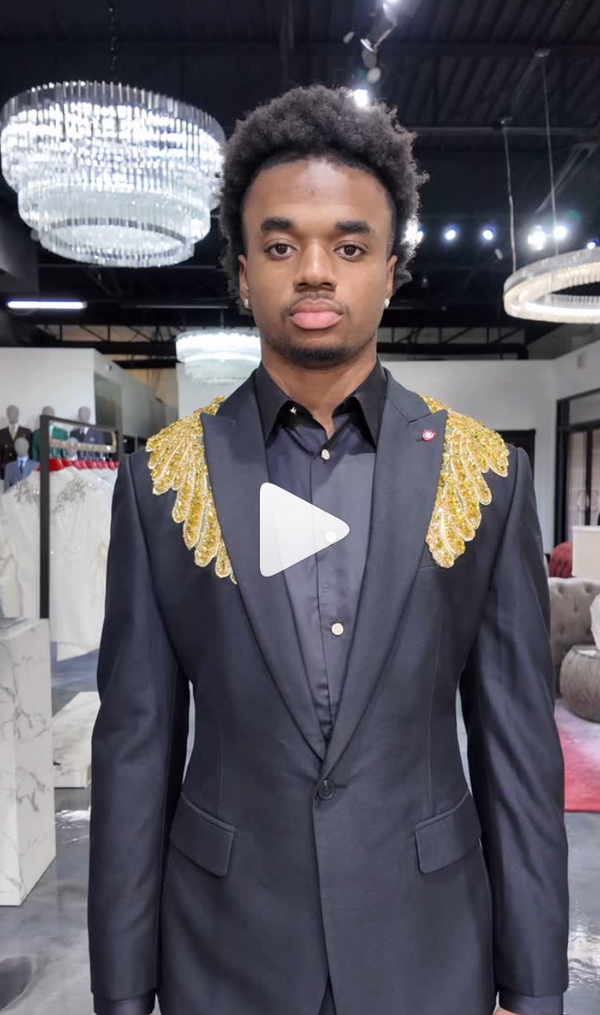 Stylish man in black suit with gold shoulders in a formal room with chandeliers