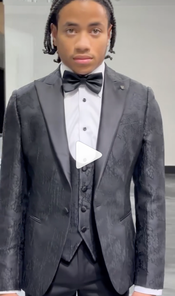 Sophisticated man in textured black tux stands poised in a bright room