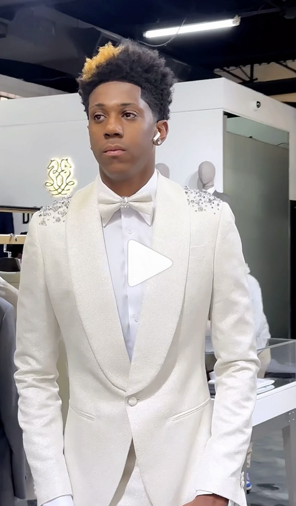Stylish man in white sequined suit standing in elegant showroom