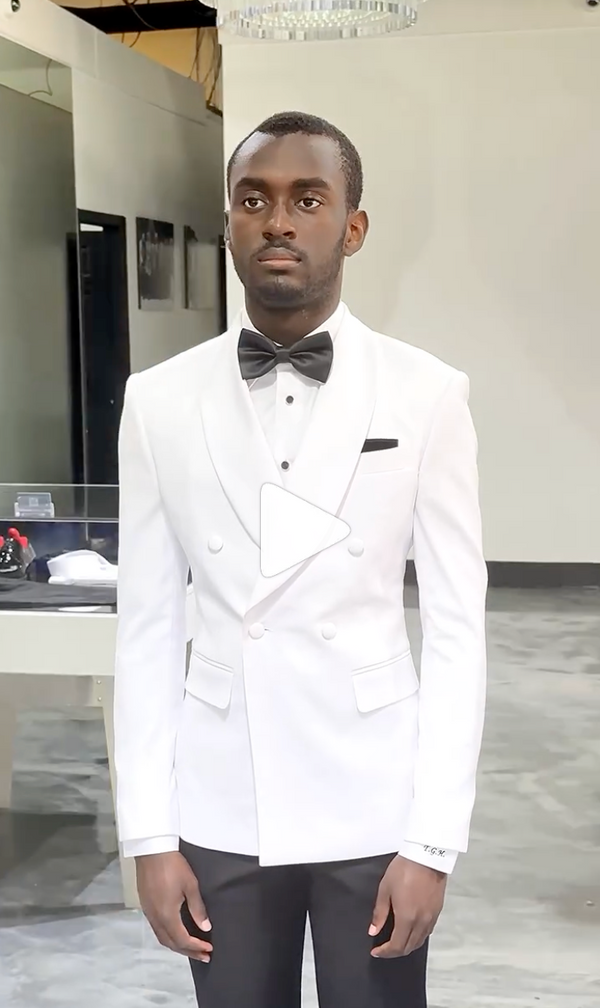 Man in white suit and bow tie stands in a calm, minimalist space