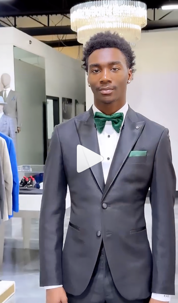 Confident man in black tux and green bow tie in stylish showroom space