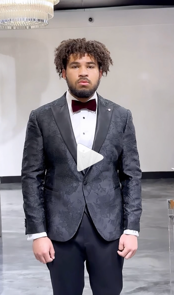 Man dressed in gray suit with bow tie posing inside a room